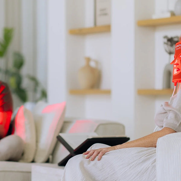Twee personen op de bank, waarvan een het Liroma LED masker voor rood licht therapie draagt