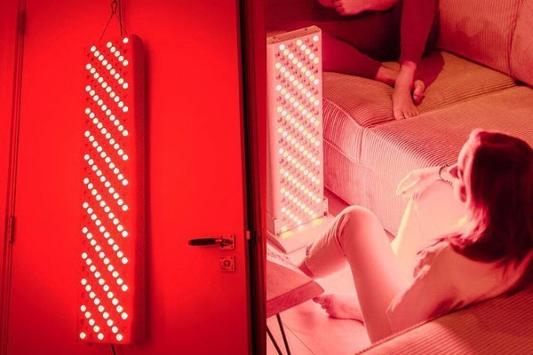 Rood licht therapie paneel aan een deur en een vrouw die ontspant bij een paneel op tafel